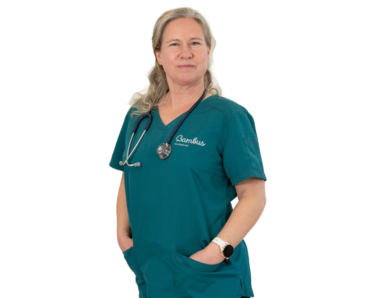 En person i blågrønn skrubbskjørt med et stetoskop rundt halsen, står med hendene i lommene mot en hvit bakgrunn.