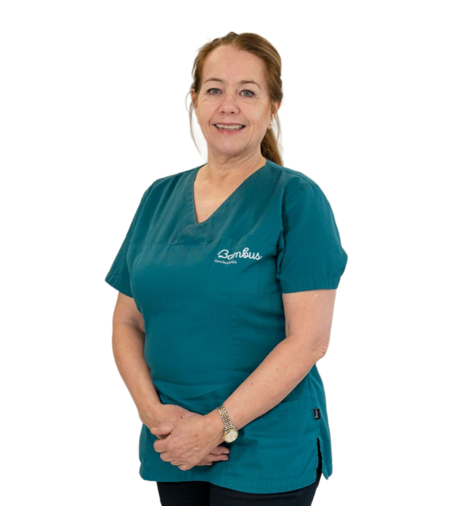 En smilende person med skulderlangt brunt hår, iført en blågrønn skrubbtopp med V-hals, står mot en hvit bakgrunn.