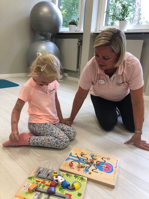 En voksen og et barn leker med pedagogiske trepuslespill på gulvet i et lyst, moderne rom.