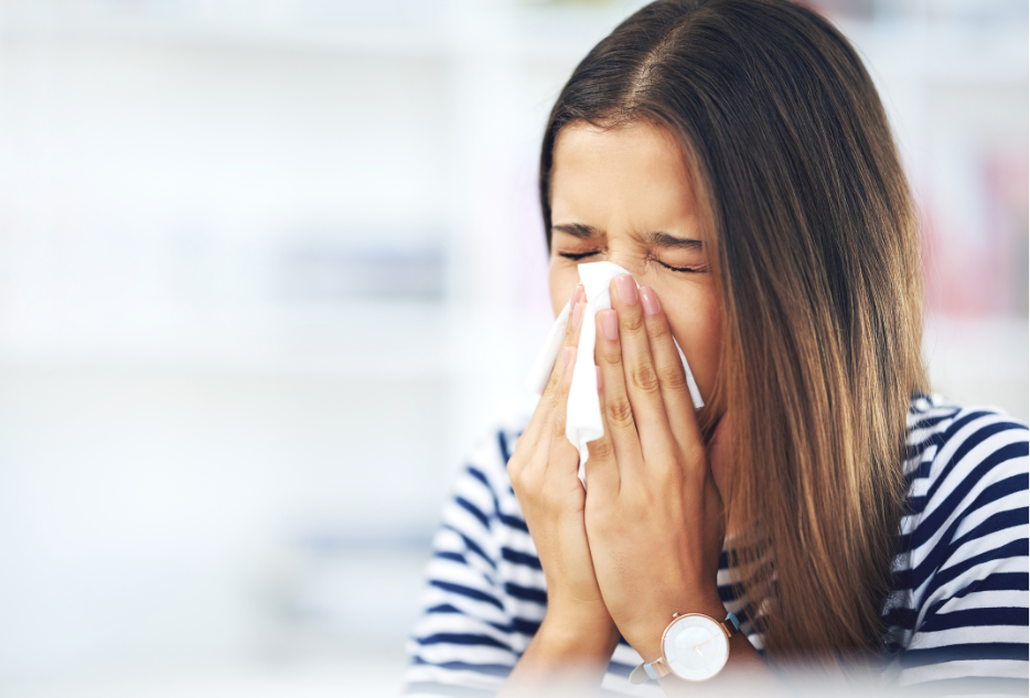 A woman sneezing potentially due to black mold present in her house due to water damage.
