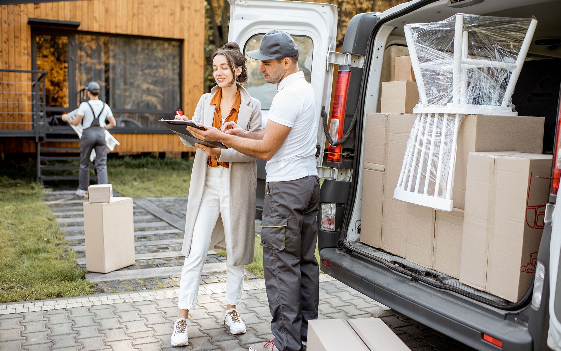 A man and a woman are standing next to a van filled with boxes.