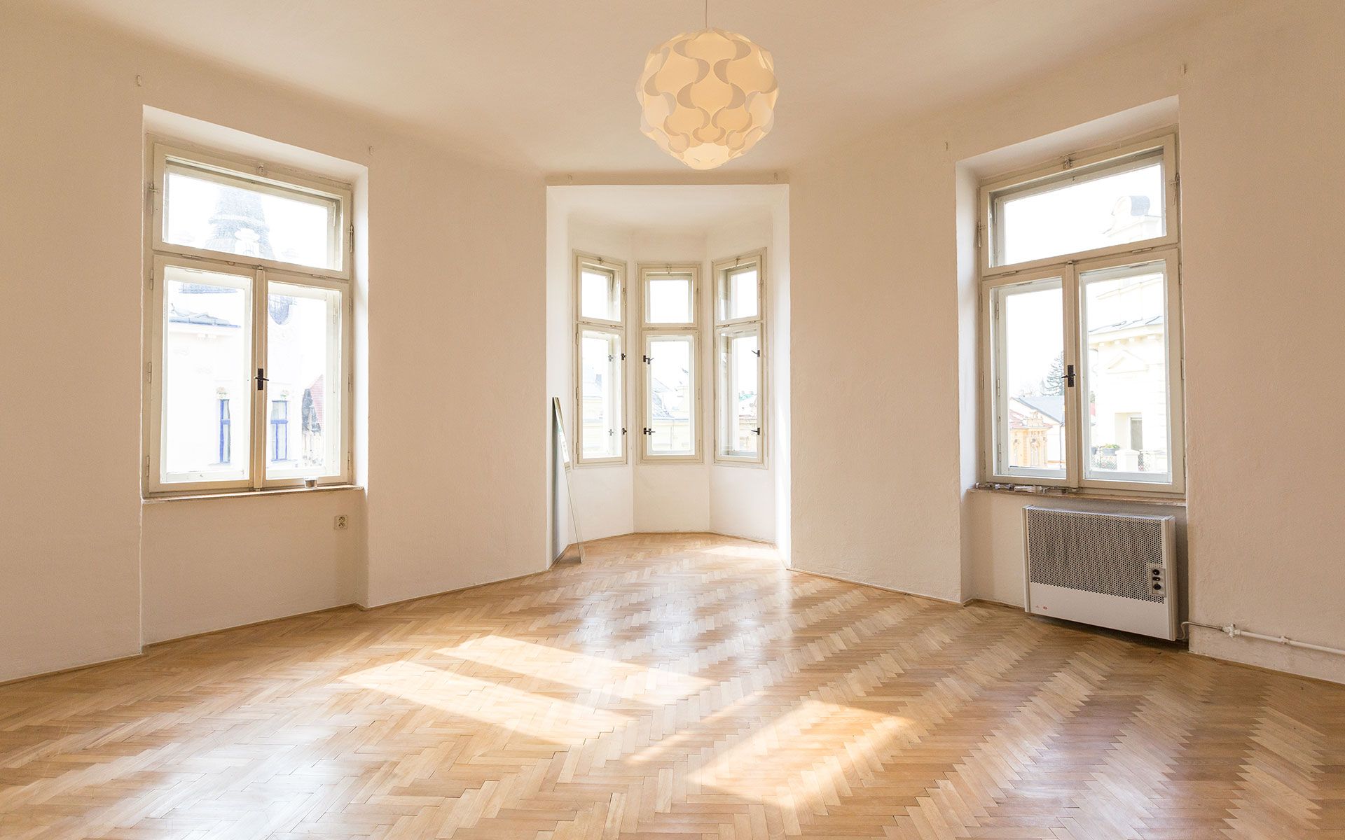 An empty living room with hardwood floors and lots of windows.