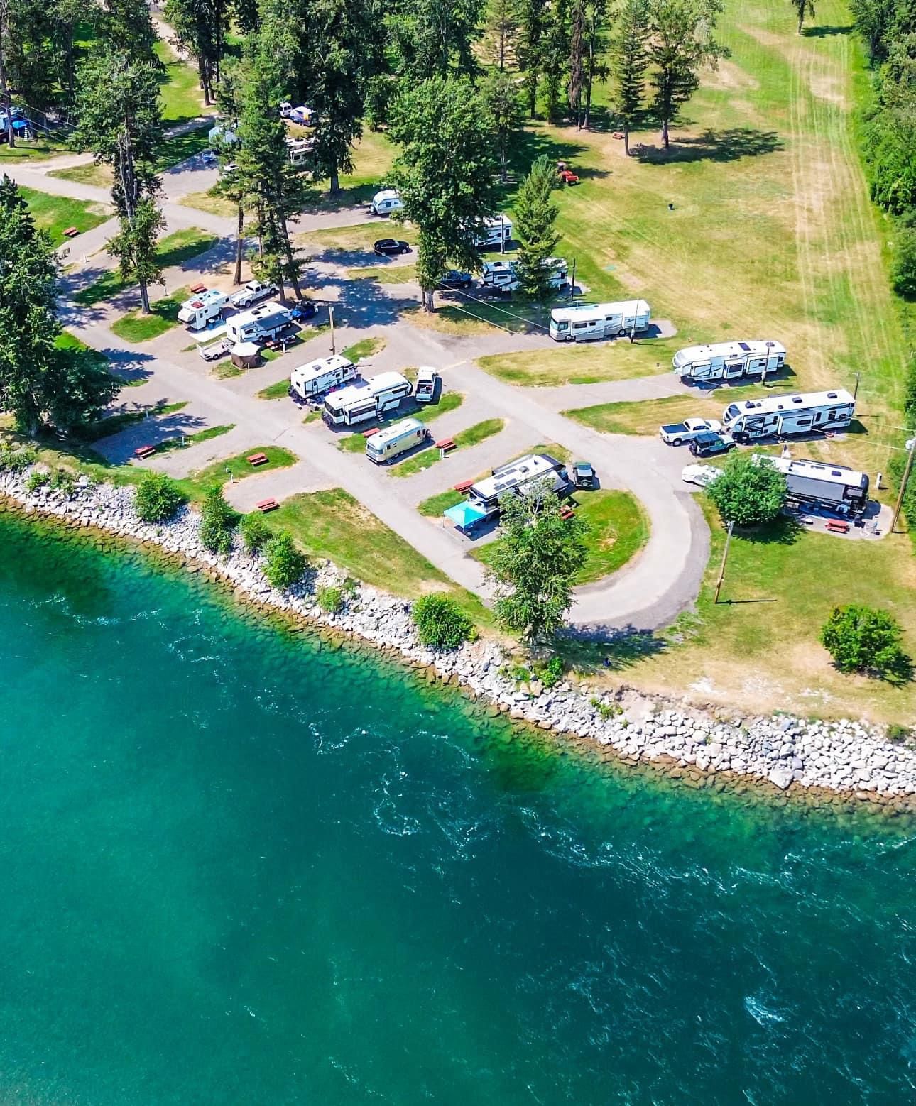 a white suv is parked on the side of a road in a park .