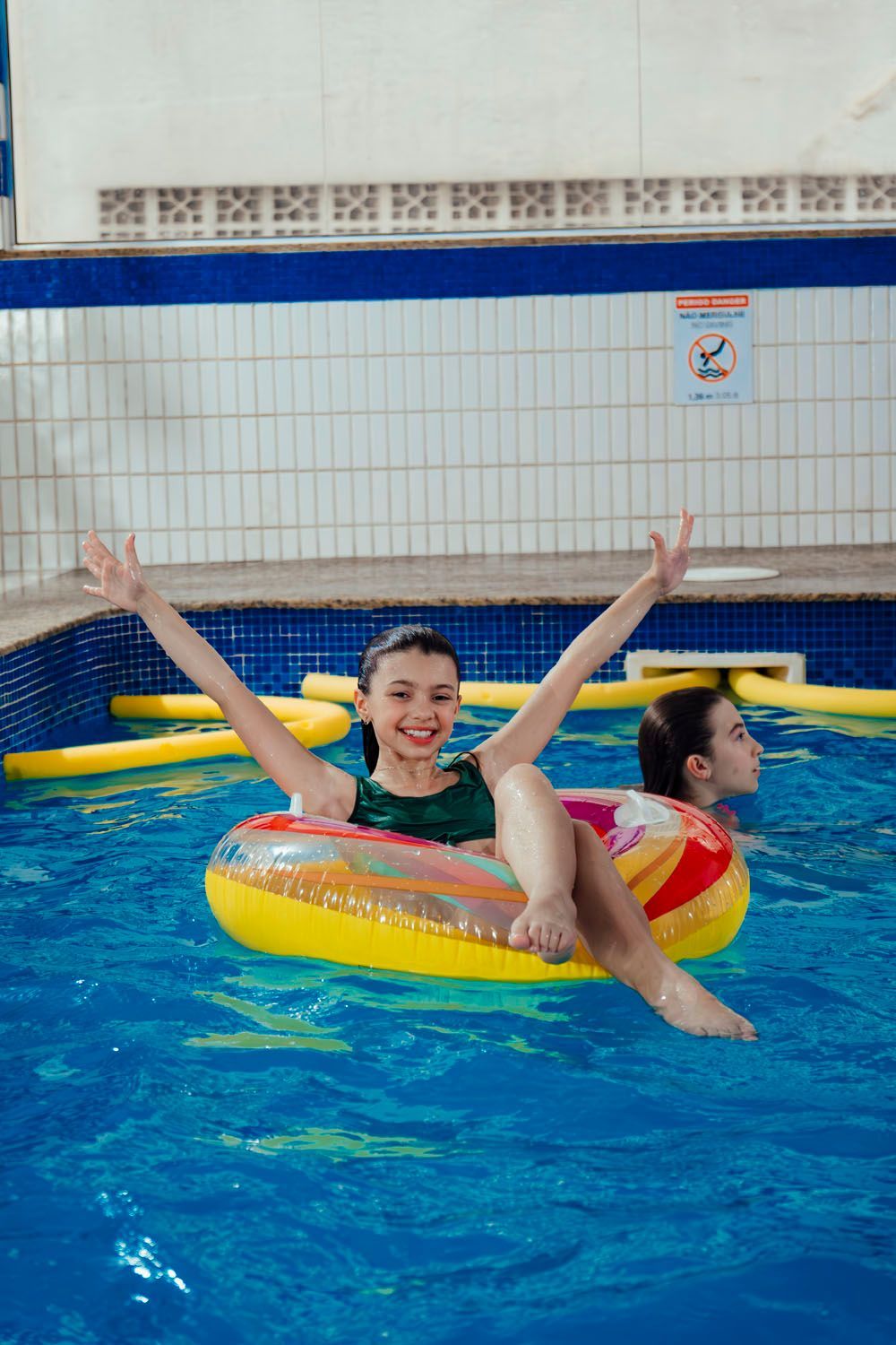 Uma garota está flutuando em um bote inflável em uma piscina.