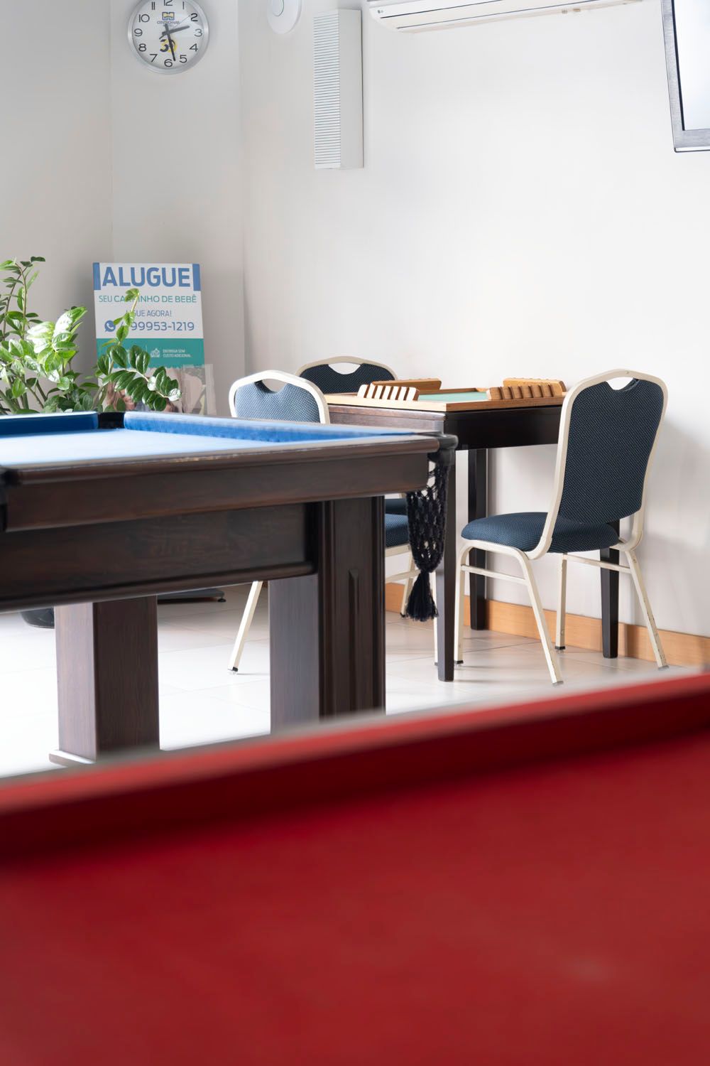 Uma mesa de sinuca em uma sala com um relógio na parede.