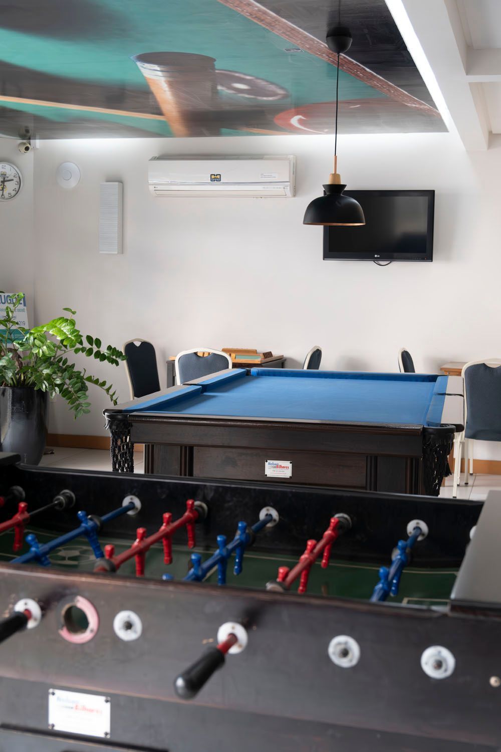 Uma mesa de sinuca e uma mesa de pebolim em uma sala