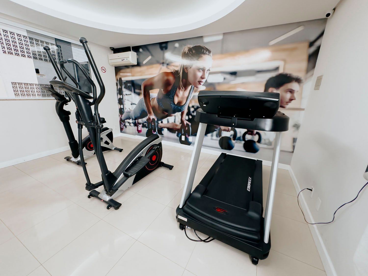 Há duas esteiras e um elíptico na sala.