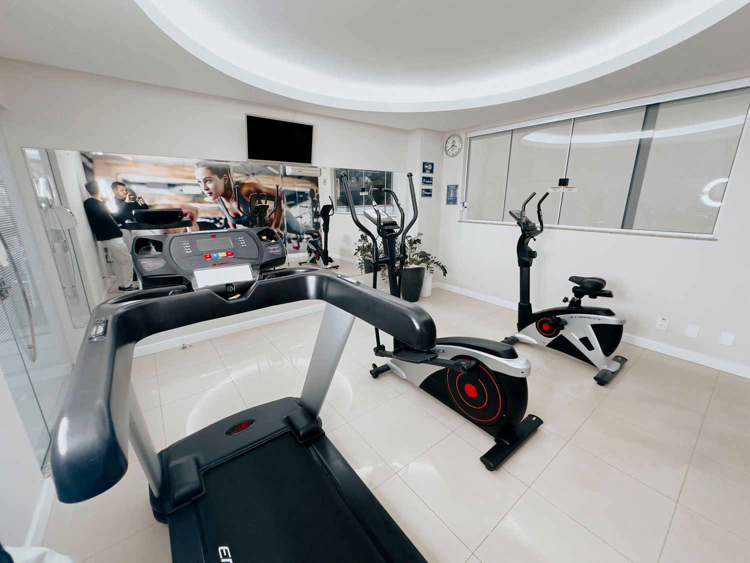 Há uma esteira e uma bicicleta na academia.