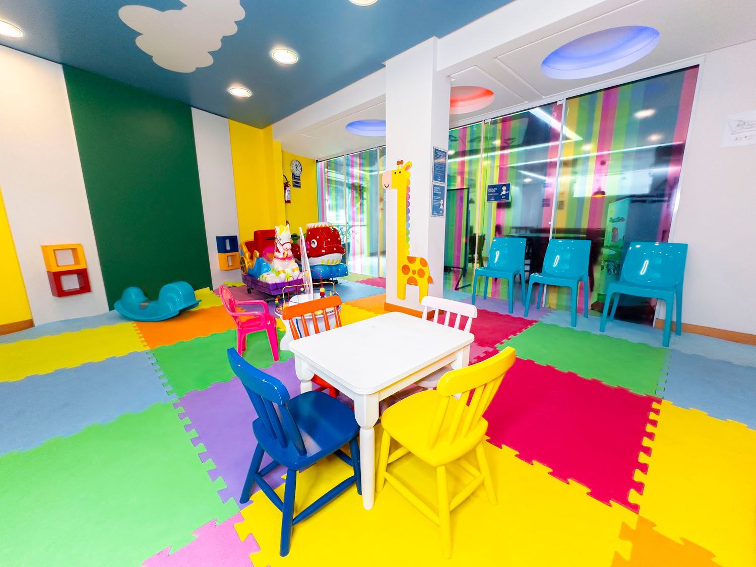 Um quarto infantil colorido com mesas e cadeiras.