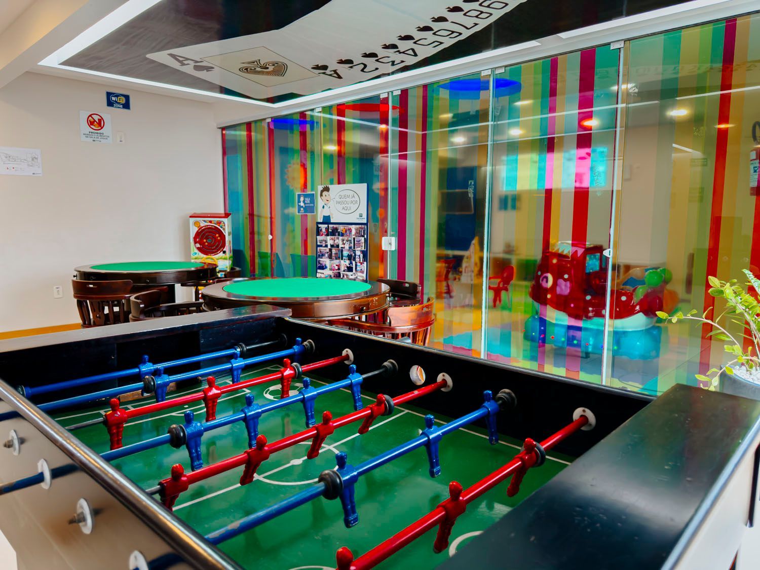 Uma mesa de pebolim em uma sala com mesas e cadeiras