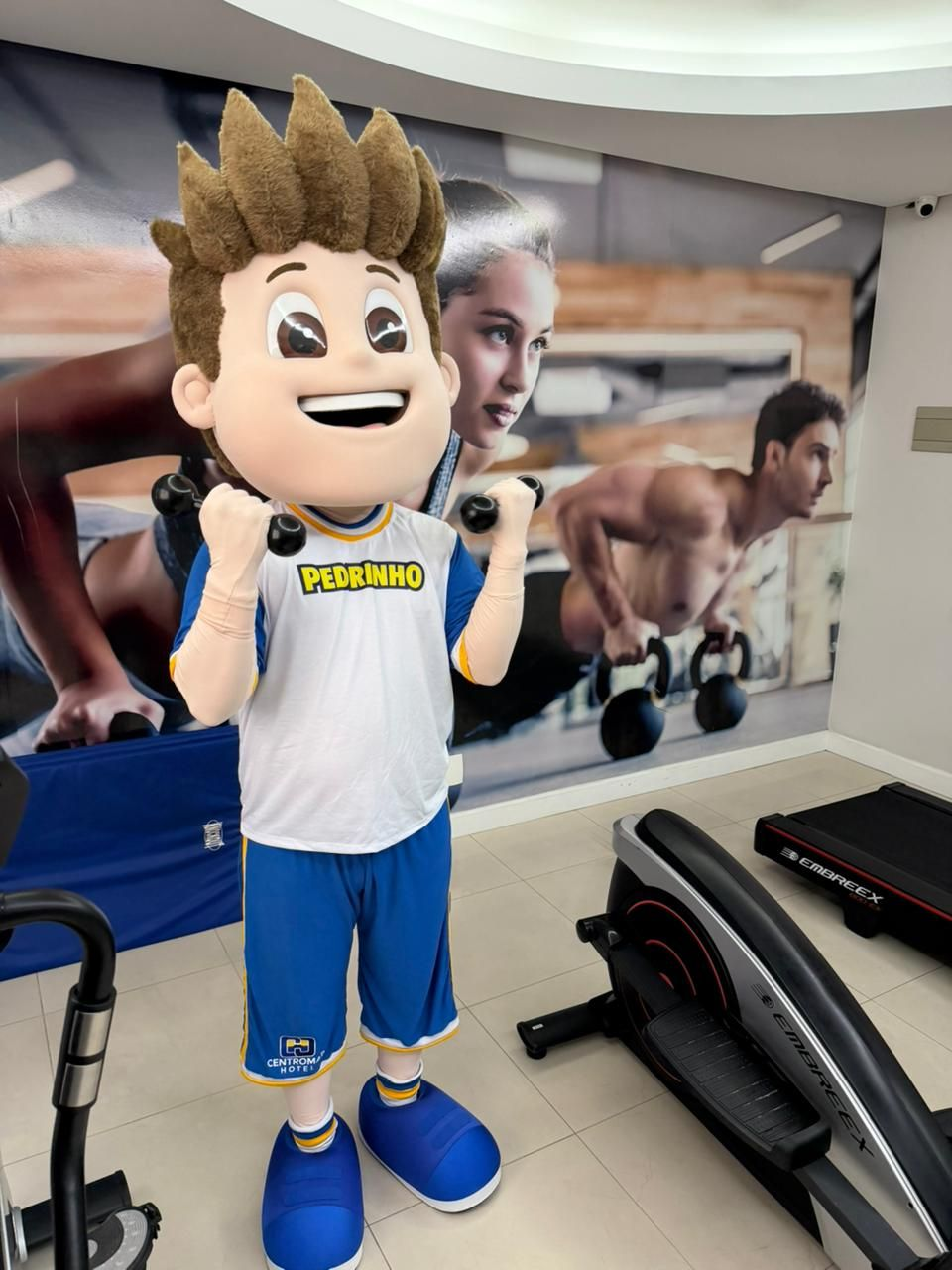 Uma academia com esteira, elíptico e outros equipamentos de exercício.