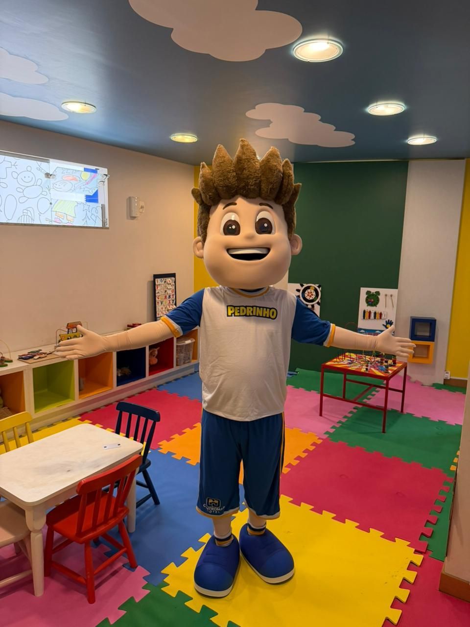 Uma sala de jogos colorida com mesas, cadeiras e uma televisão.