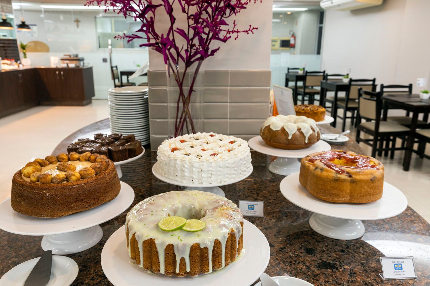 Uma variedade de bolos são expostos em uma mesa em um restaurante.