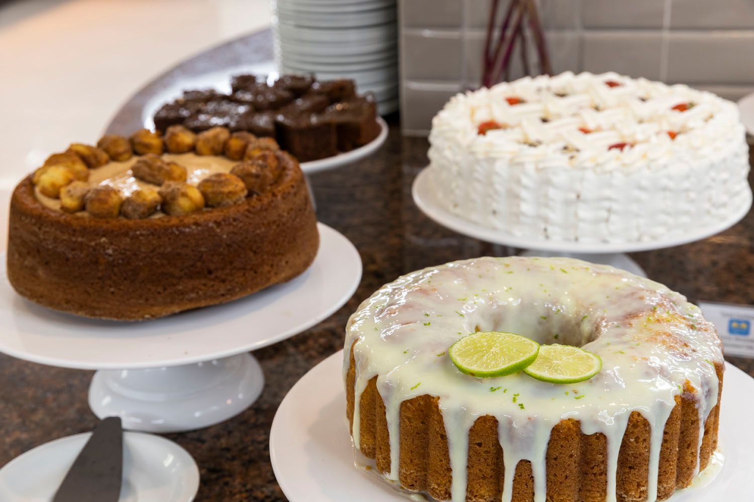 Uma variedade de bolos estão expostos em uma mesa.