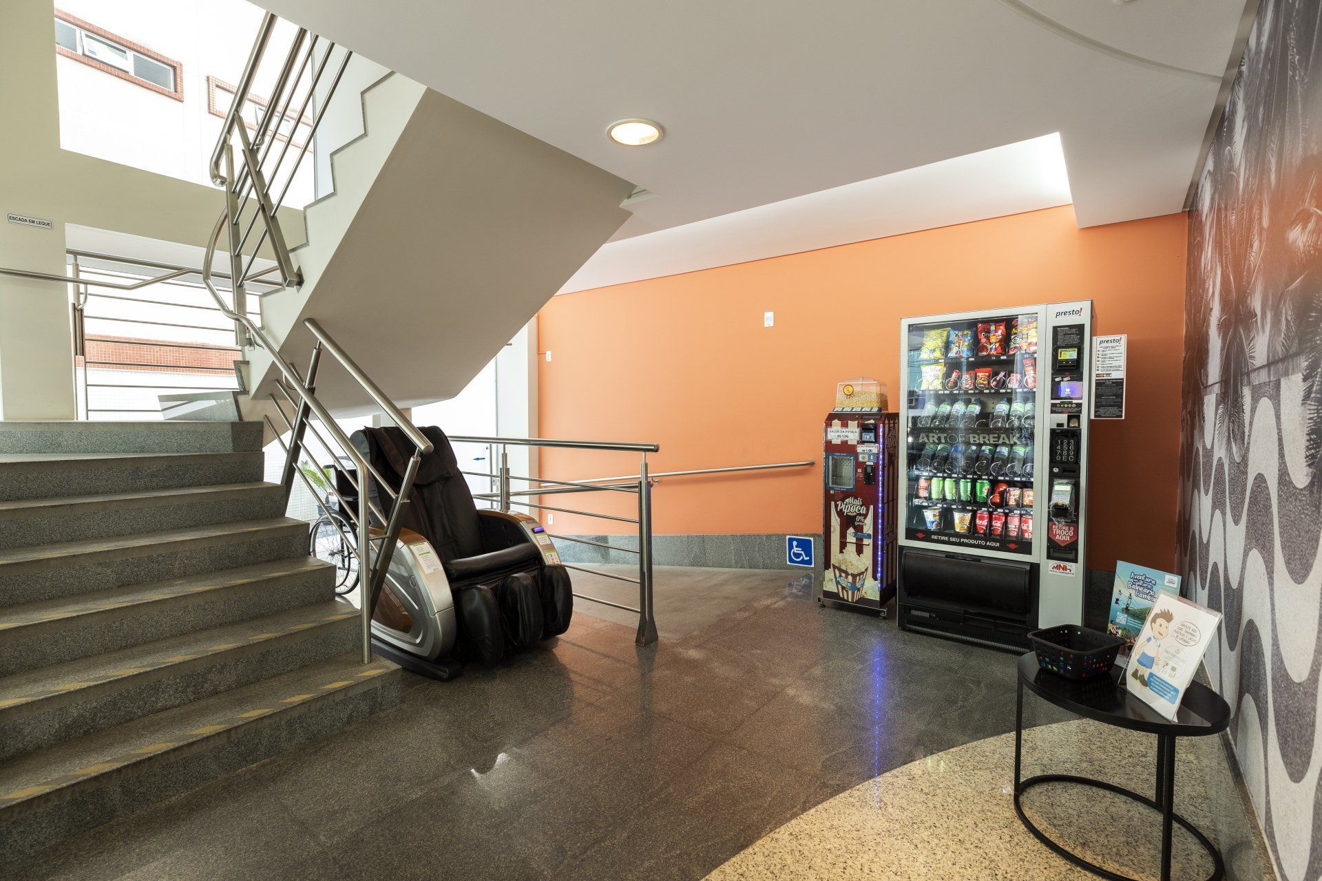 Uma escada com uma cadeira de massagem e uma máquina de venda automática