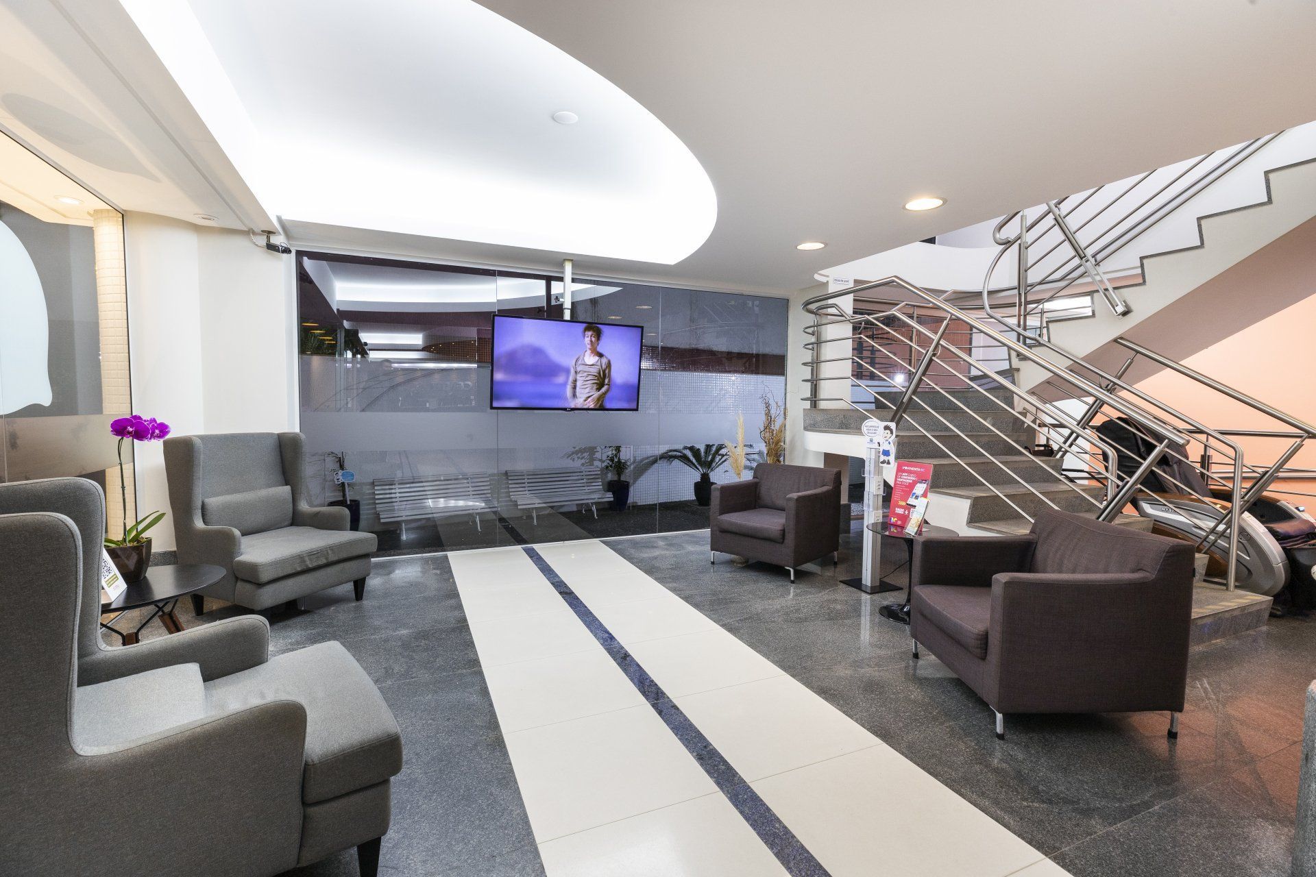 Um lobby com cadeiras e uma televisão na parede