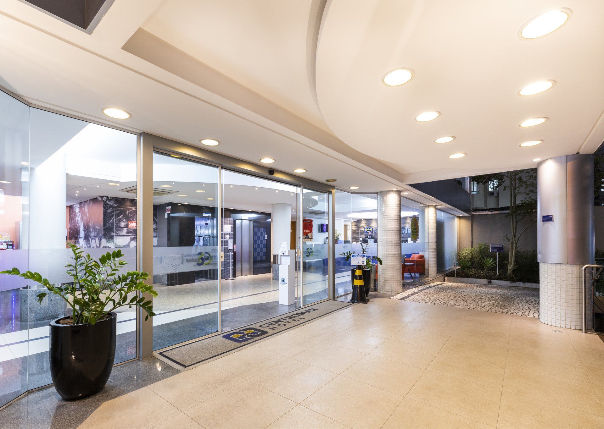 Um grande lobby com portas de vidro deslizantes e uma planta em vaso.