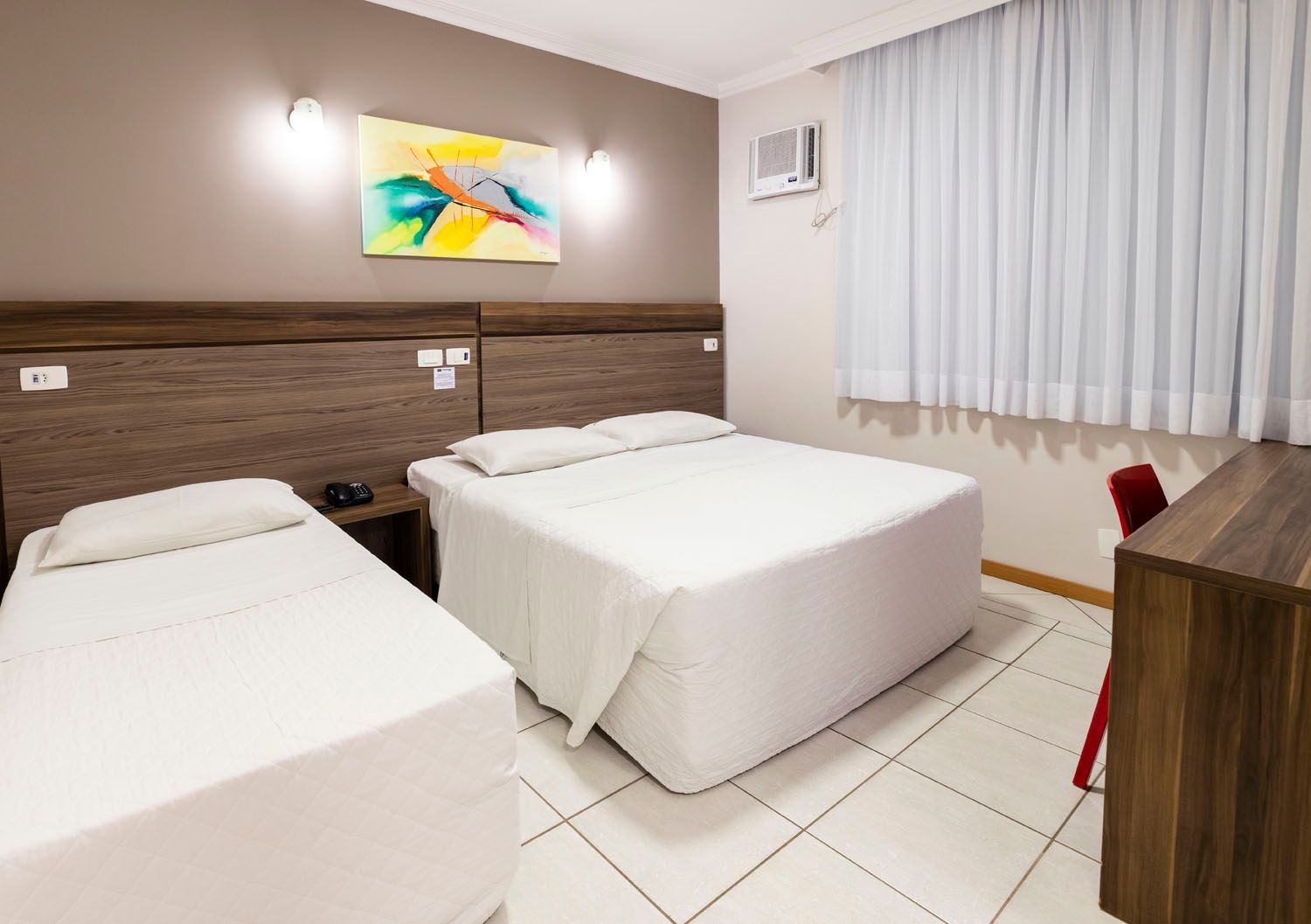 Um quarto de hotel com duas camas e uma escrivaninha.