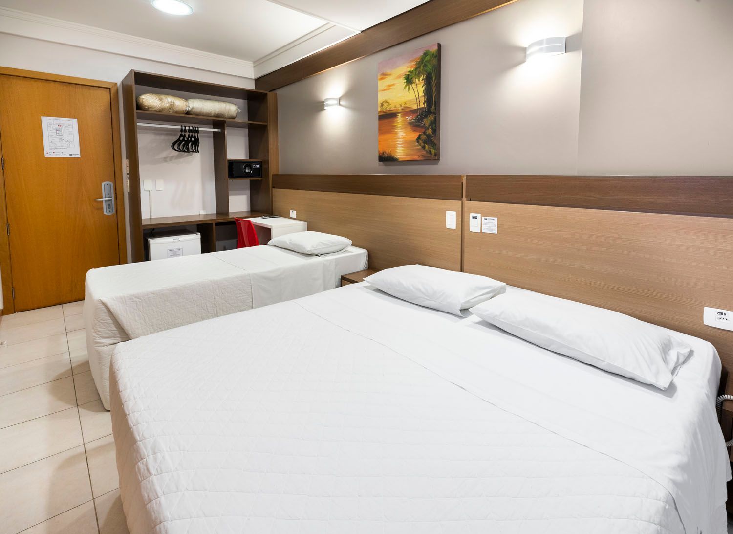 Um quarto de hotel com duas camas e uma pintura na parede.