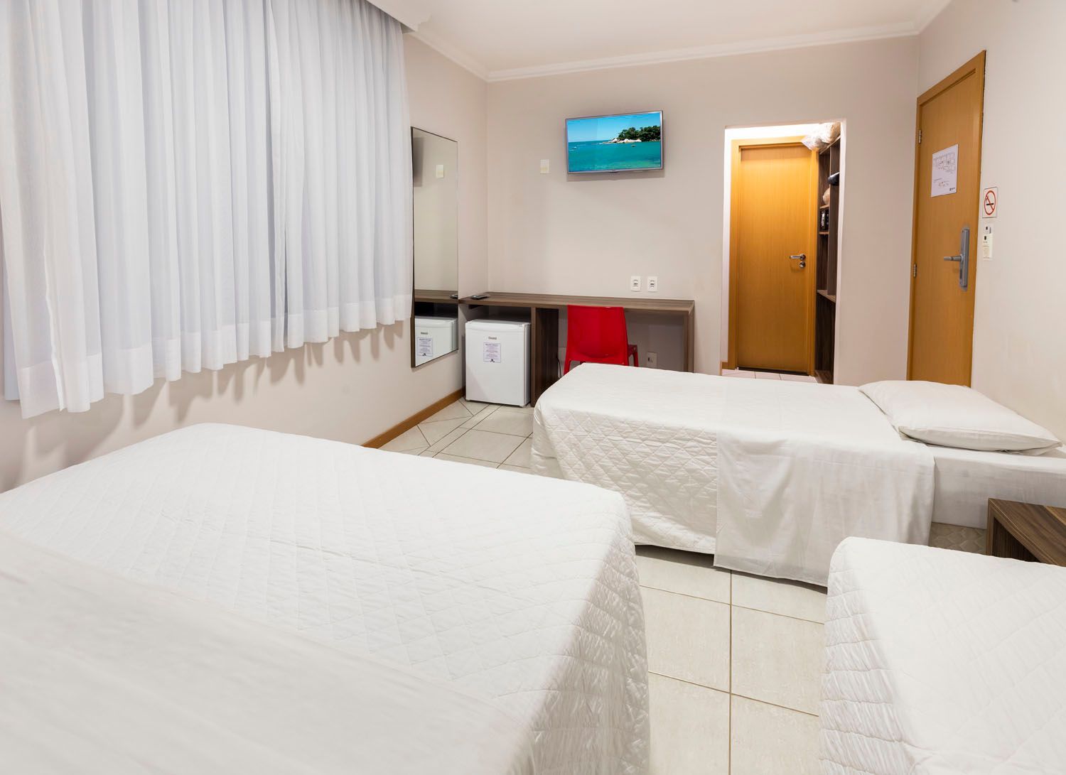 Um quarto de hotel com duas camas e uma televisão.