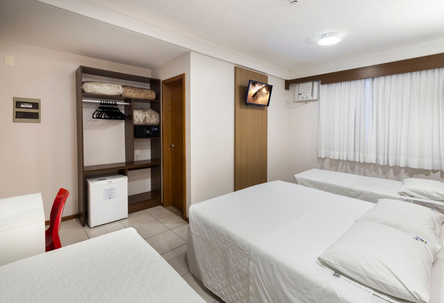 Um quarto de hotel com duas camas e uma televisão.