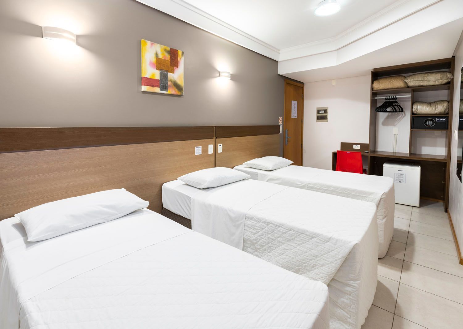 Um quarto de hotel com três camas e uma pintura na parede.