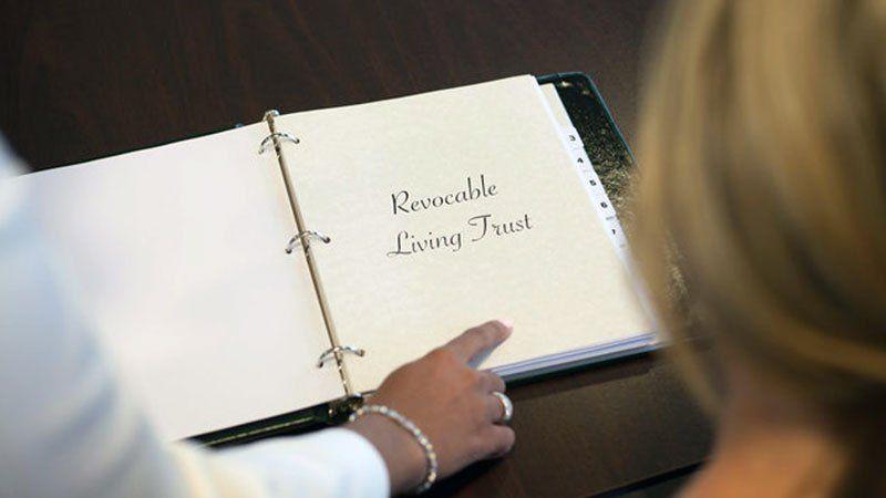 people looking at binder that says revocable living trust