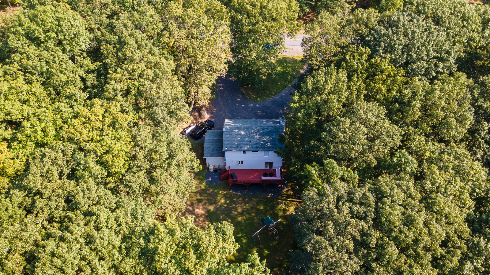 An aerial view of a house in the middle of a forest.