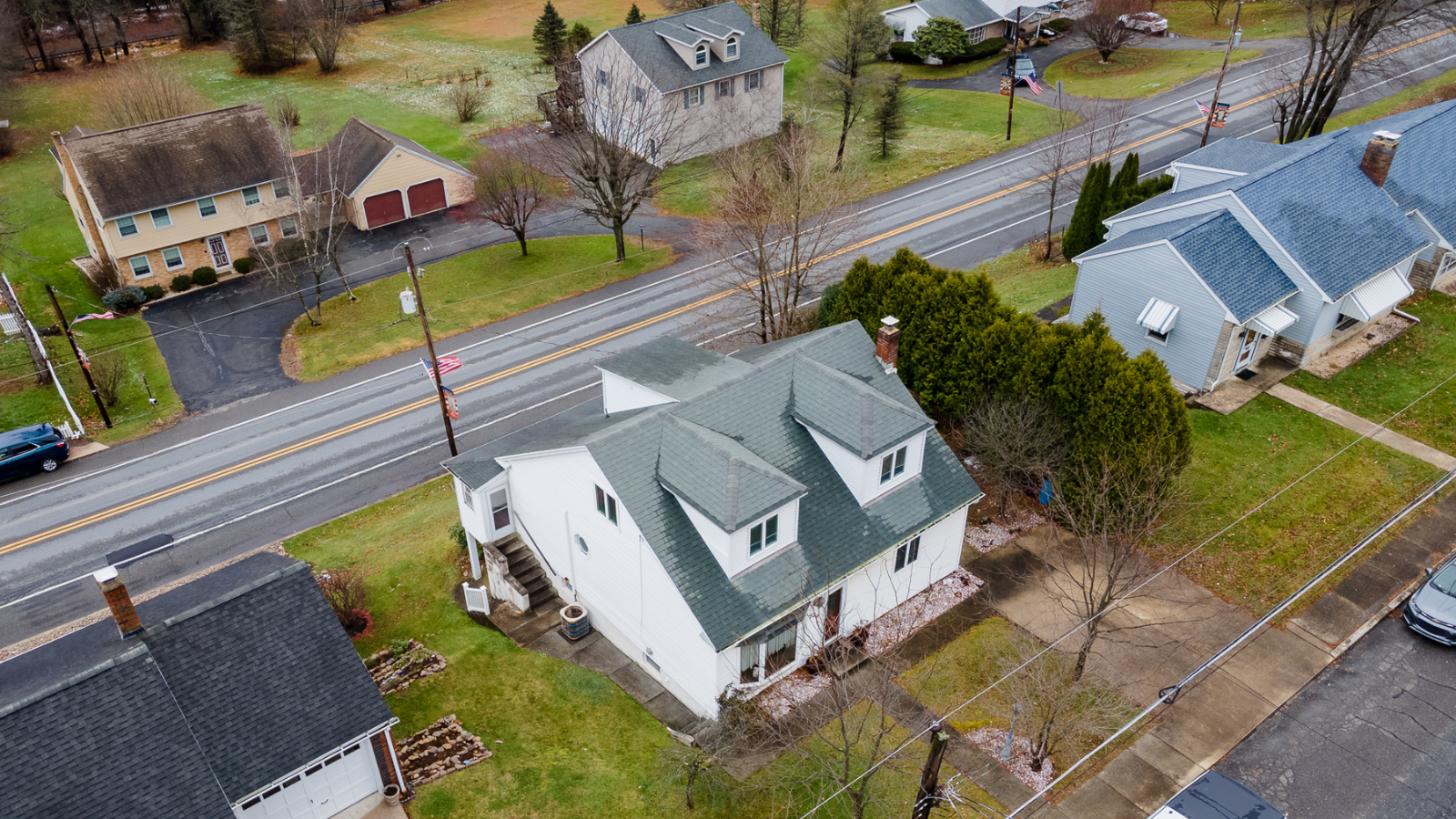 An aerial view of a house with a green roof next to a road.