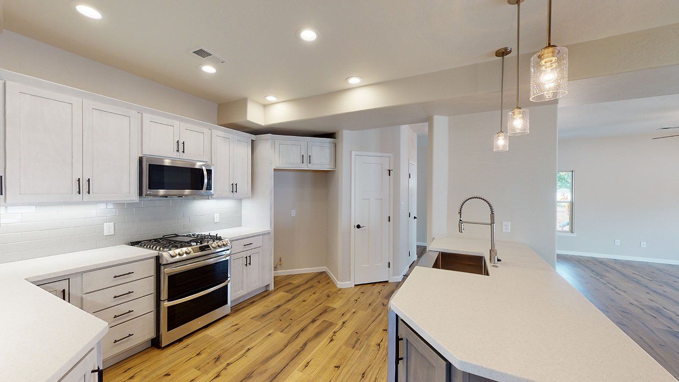 Luxurious kitchen space with quartz countertops, white cabinets, and pendant lighting