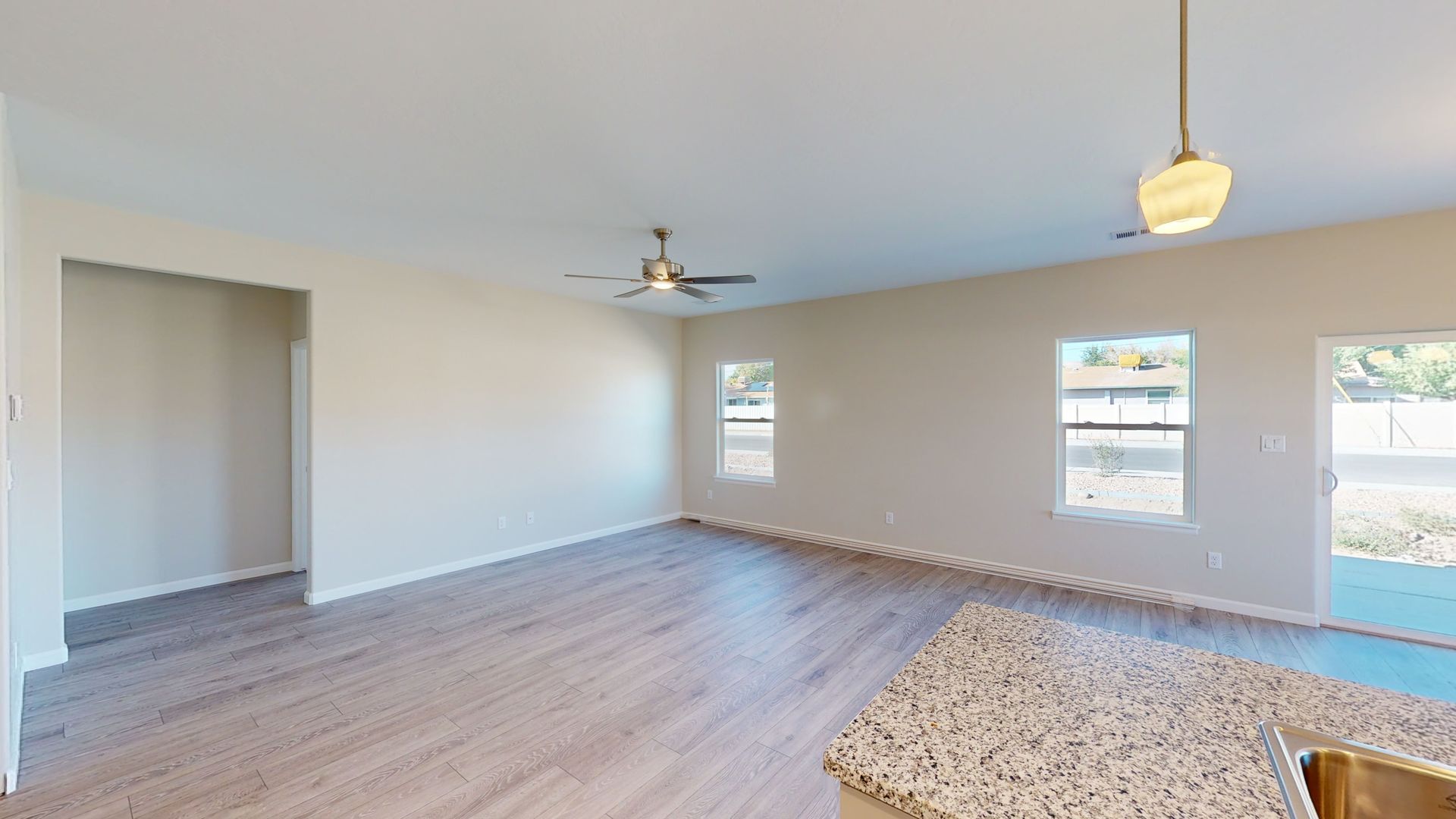 Great room with ceiling fan and granite kitchen counter