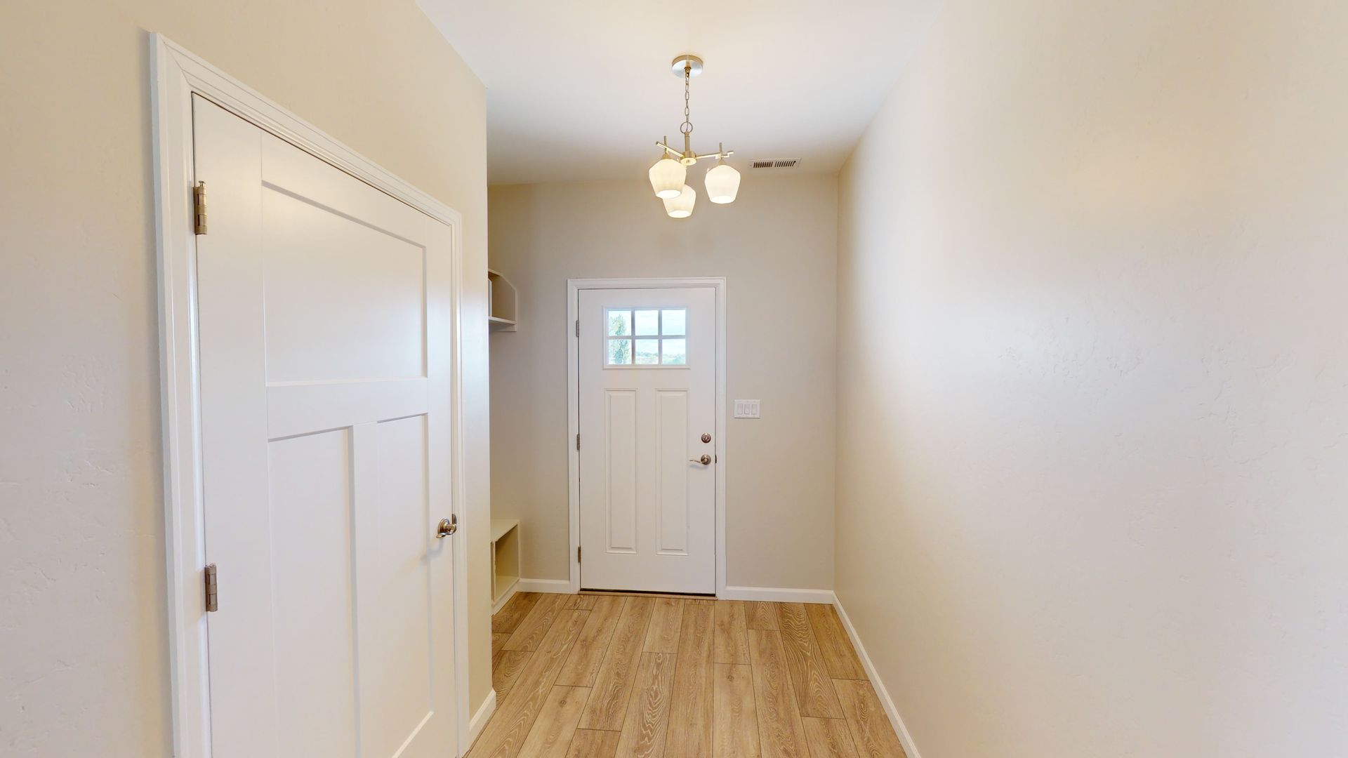 Neutral entry with white door wood floors and traditional lighting 