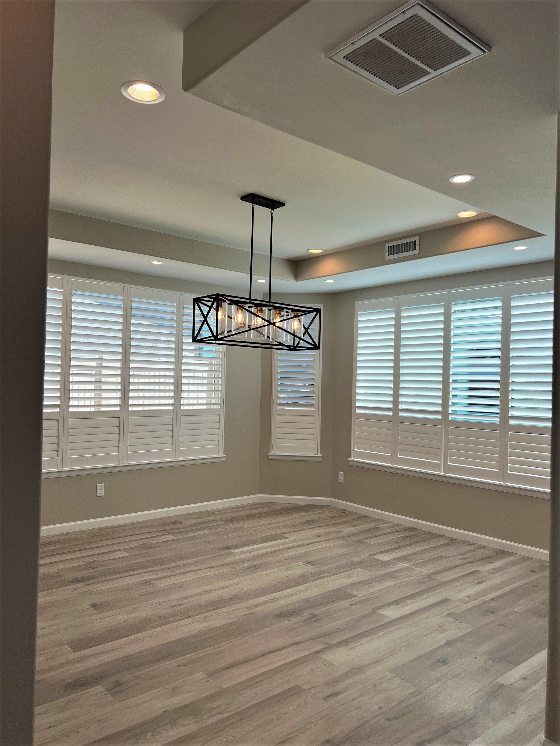 Luxury Dining room with trey ceiling, window covered walls, and modern chandelier 