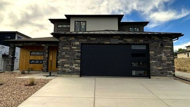 Elegant modern home exterior with stone wood and stucco.