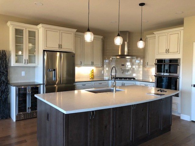 Kitchen white cabinets, quartz counters, pennate lights, and stainless steel appliances