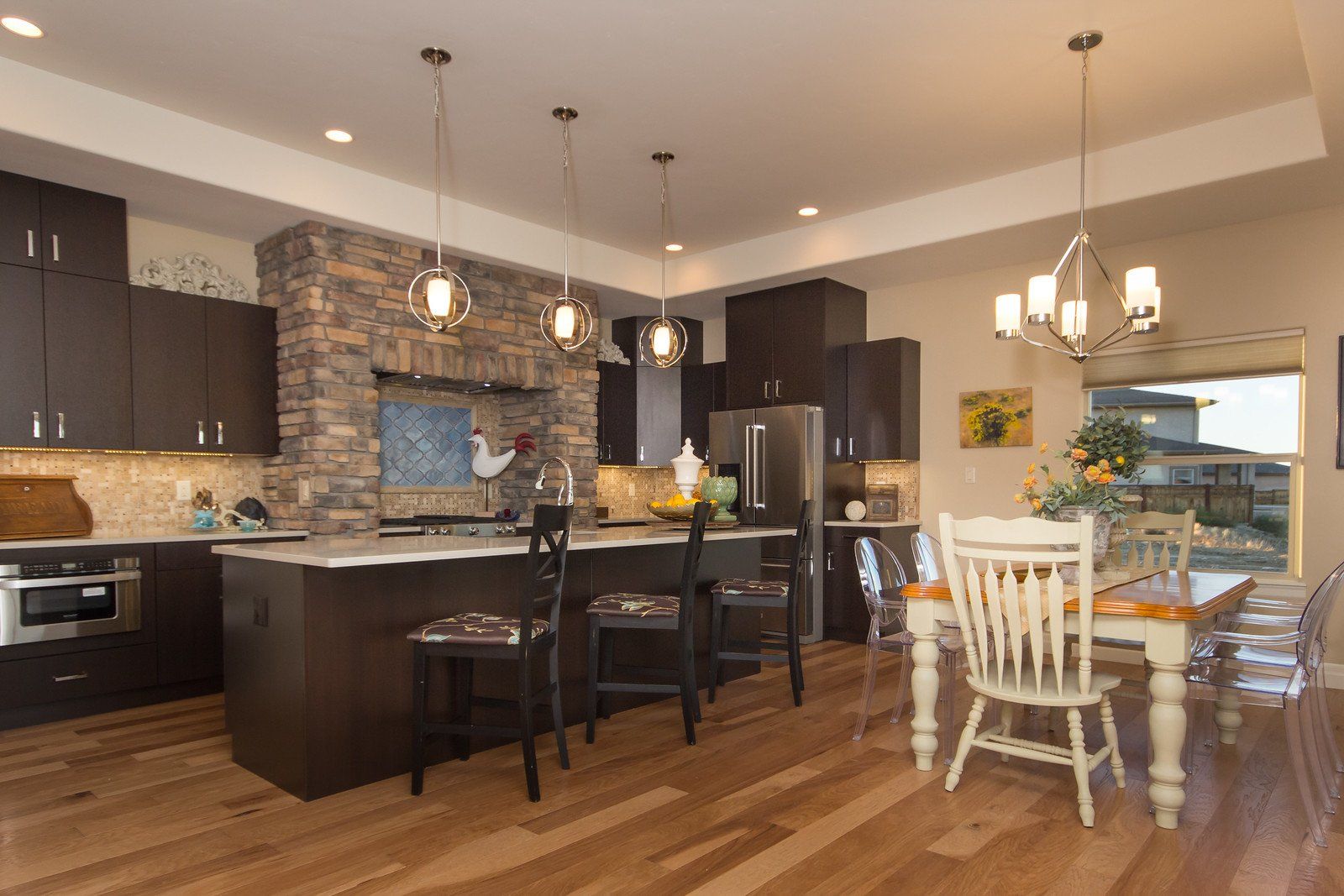 Kitchen with Brick Range Hood and Island with Seating and Dining Room | Integrity Homes | Grand Junction, CO 81501