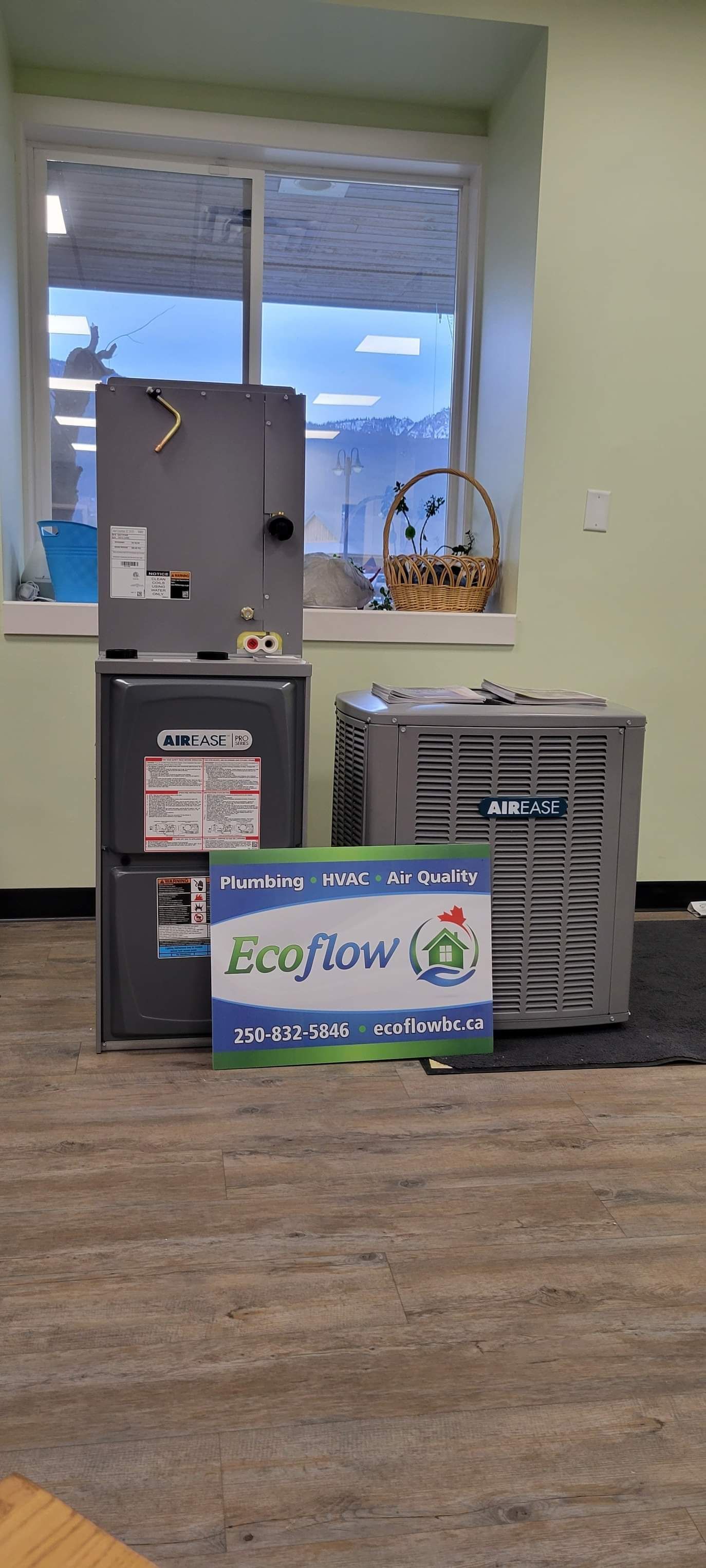 two air conditioners are stacked on top of each other in a room next to a window .
