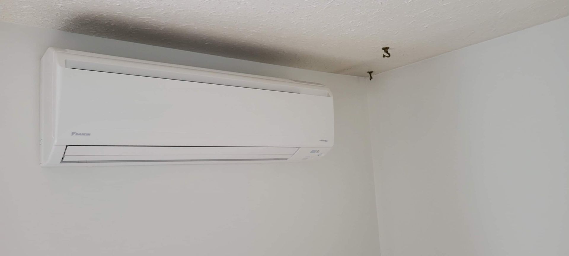 A man is working on an air conditioner in a basement.