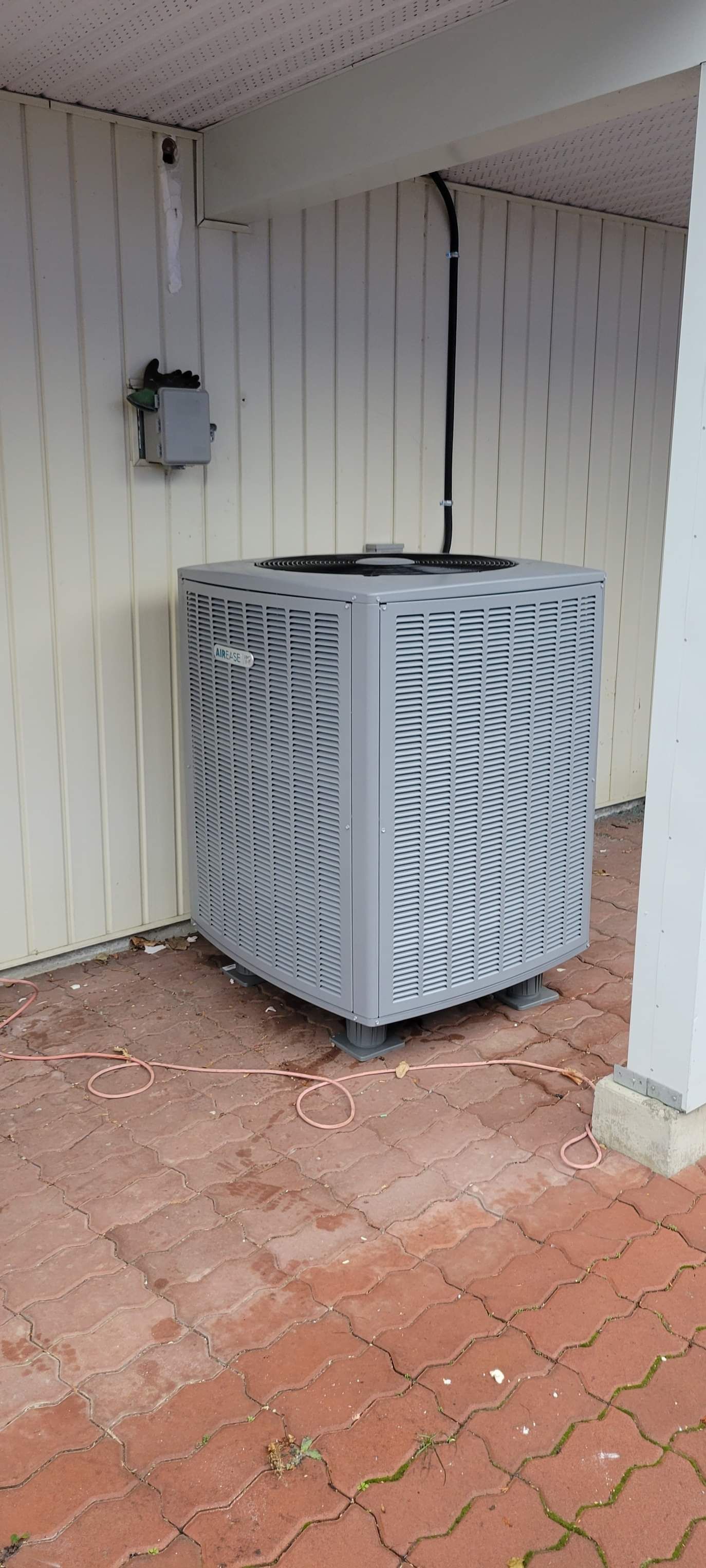 a large air conditioner is sitting on a brick sidewalk next to a building .