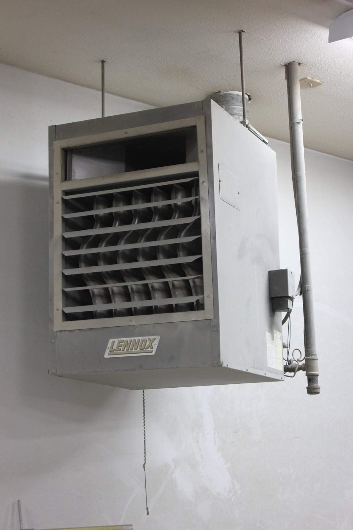 a large heater is hanging from the ceiling in a room .