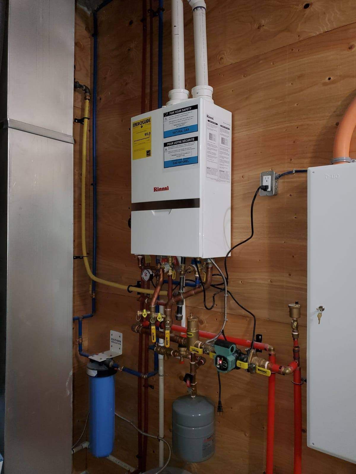 A white water heater is hanging on a wooden wall.