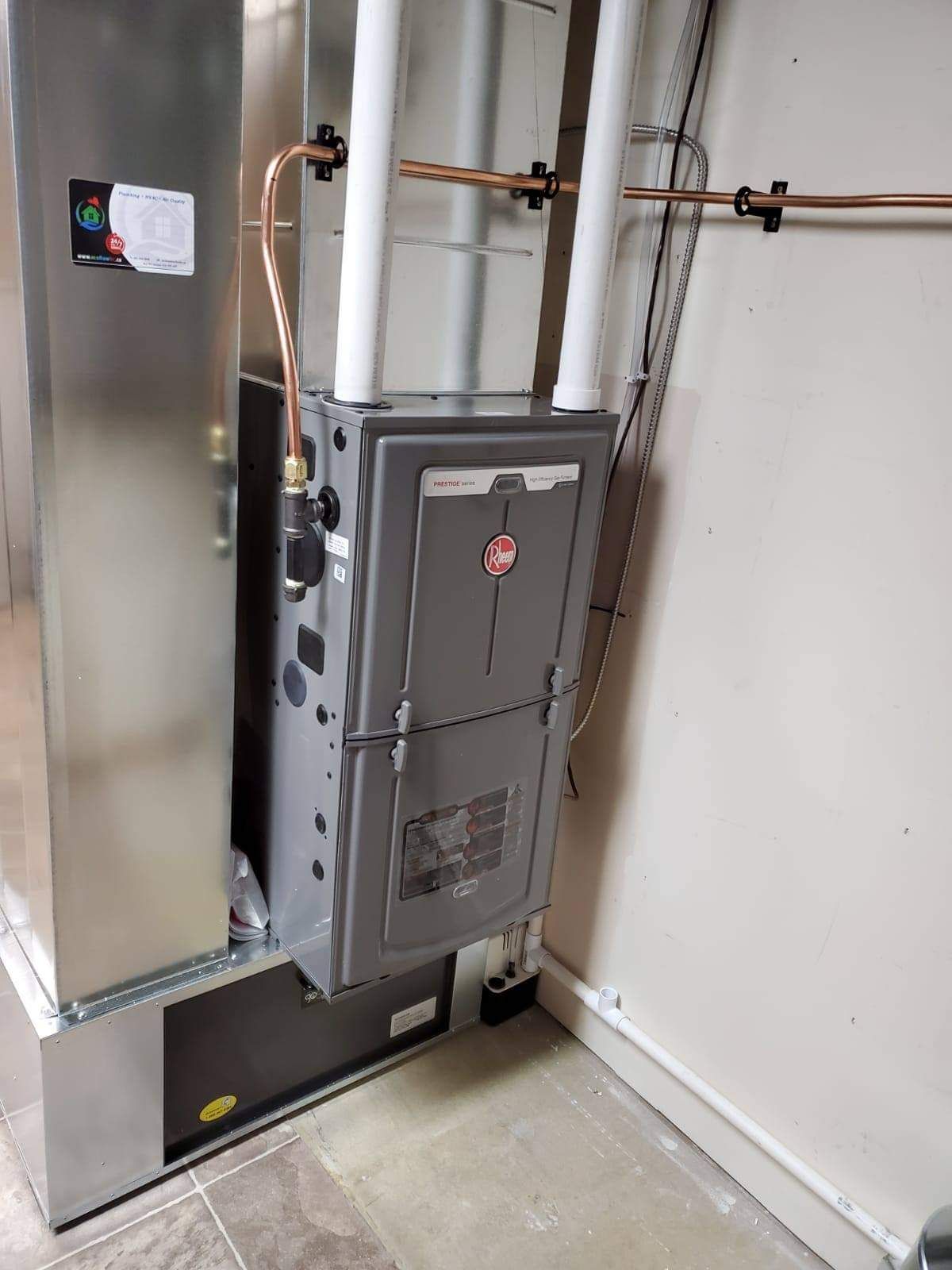 a stainless steel furnace is sitting in a room next to a wall .
