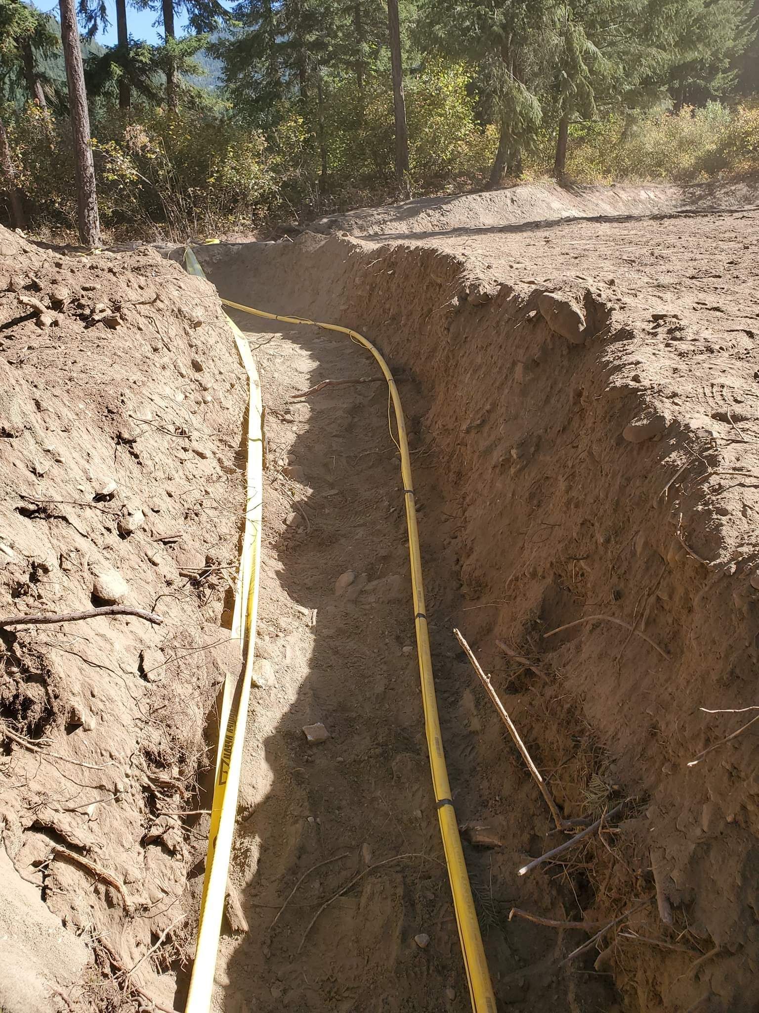 a yellow hose is laying in the dirt in a trench .