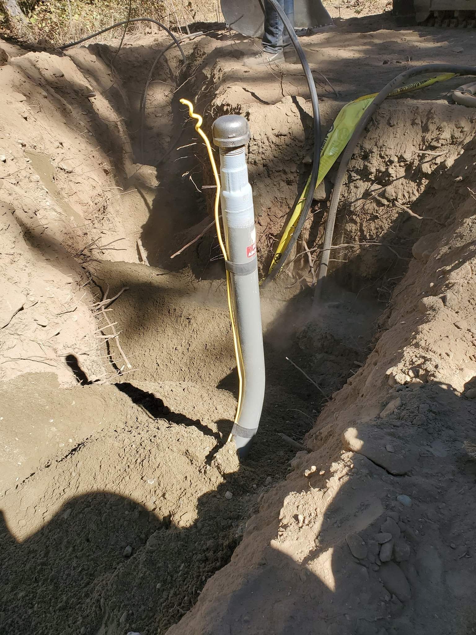 a person is digging a hole in the ground to install a pipe .