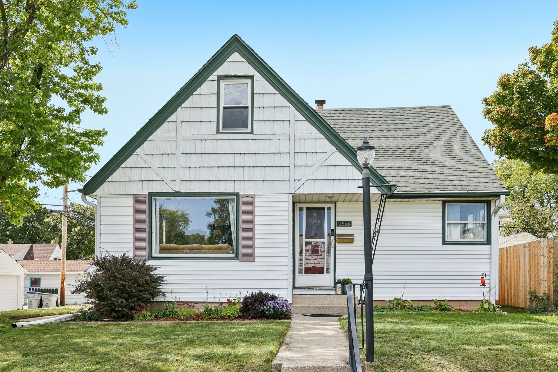 Milwaukee, WI home with green trim and a small front yard on a sunny day.