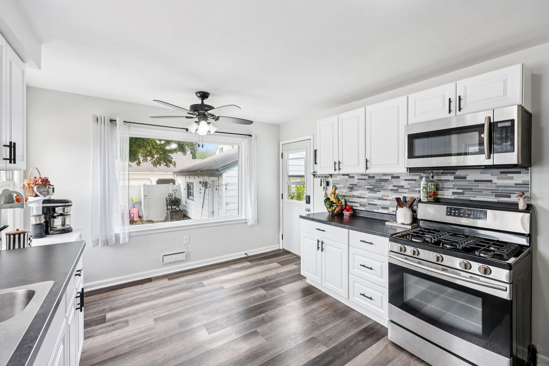 Modern kitchen with white cabinets, stainless steel appliances, and dark countertops.