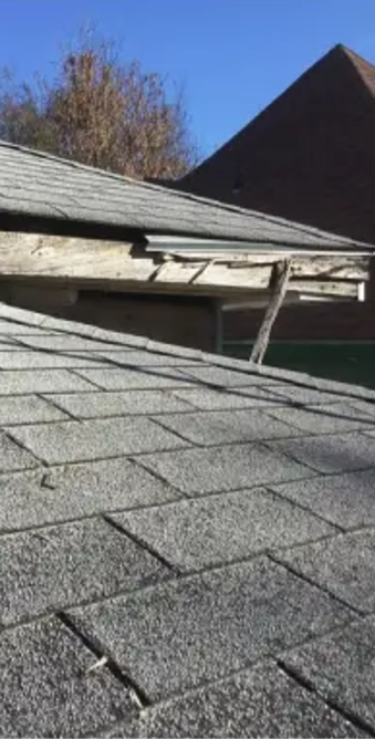 Close-up of a damaged roof edge, showing broken wood and exposed structure with a blue sky background.