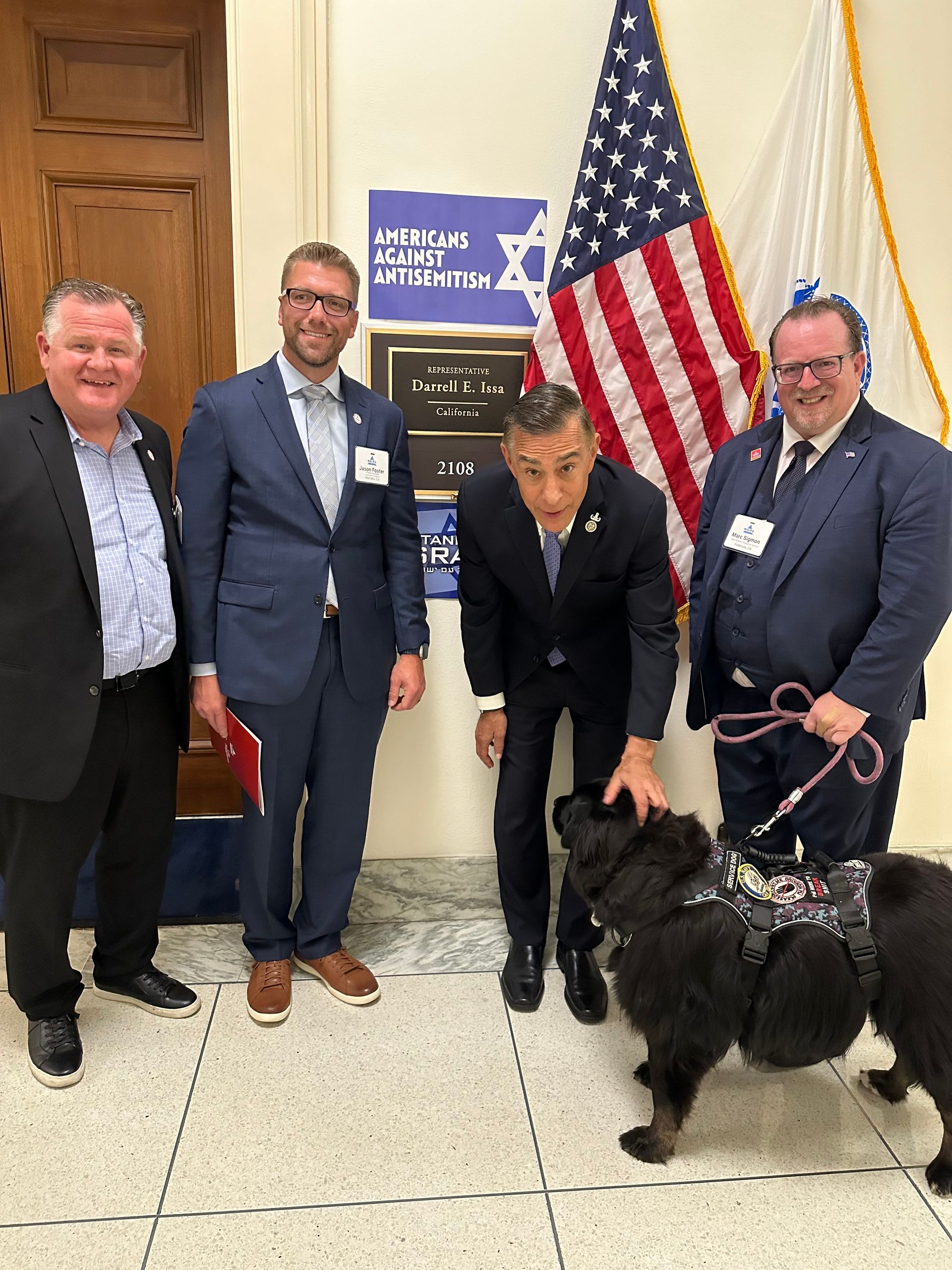 A group of men standing next to a dog in front of an american flag