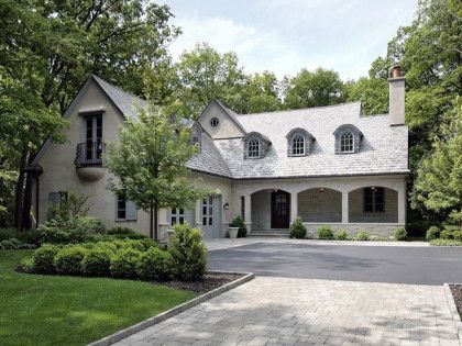 A large house with a large driveway in front of it surrounded by trees.