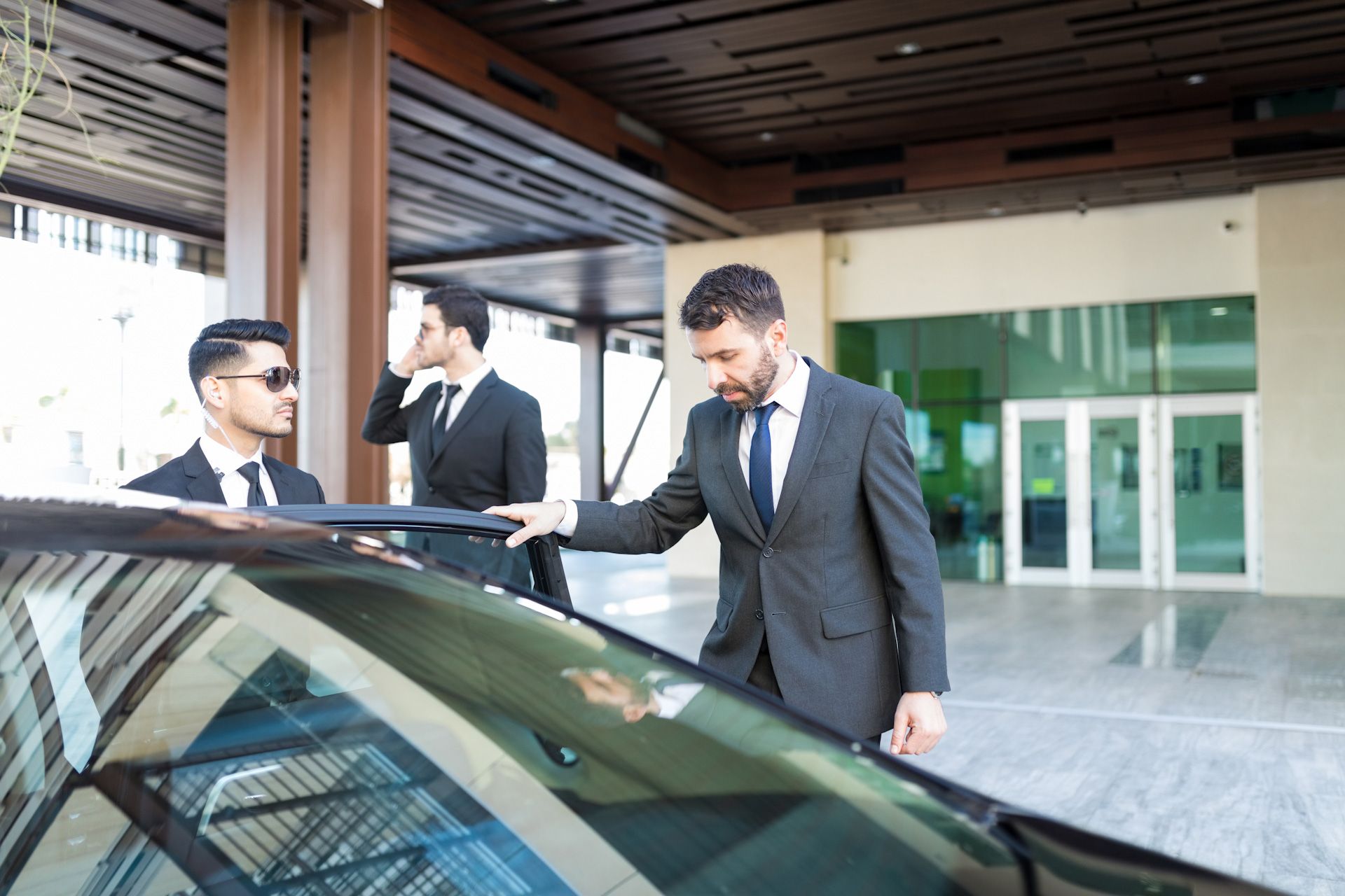 A man in a suit and tie is standing next to a car.